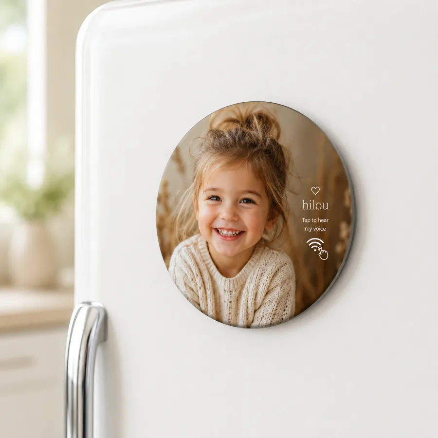 A round hilou photo magnet of a smiling child on a fridge, reading 'Tap to hear my voice'